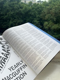 an open book on a window sill with a tree in the background