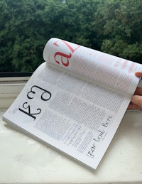 a person holding a magazine on a window sill